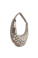 Cartera tipo hobo de Las Oreiro en color beige, con diseño de media luna y decorada con tachas metálicas plateadas en toda su superficie frontal. Incluye una correa fija y un dije colgante con el logo de la marca.