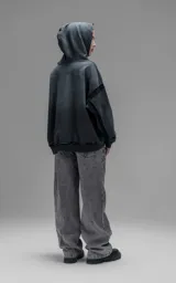Hoodie oversize de corte crop en color gris oscuro con efecto desgastado. Presenta costuras expuestas, detalles de roturas en el ruedo y en la capucha, y bolsillos frontales con bordes reforzados.