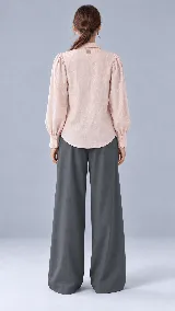 Camisa de color crudo con cuello camisero clásico, mangas abullonadas con puños estructurados terminados en ondas y delicados bordados florales en la parte frontal.