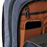 Mochila de color azul marino con diseño acolchado en el panel frontal. Presenta un parche de cuero marrón con logo grabado en la parte inferior central del frente. Los bordes y cierres son de color negro.