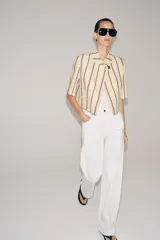 Blazer cropped ZW Collection confeccionada en mezcla de algodón, con diseño a rayas verticales en tonos azul y rojo sobre base beige. Presenta cuello redondo, manga corta, forro interior a tono y cierre frontal con un botón.
