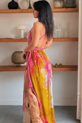 Vestido largo de seda con estampado abstracto en tonos marrones, beige y destellos dorados, con escote en V profundo, tirantes de cuerda anudados al cuello y la cintura, y tajo lateral en la falda.