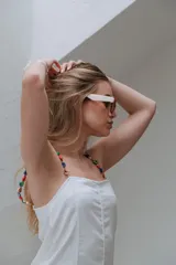 Vestido corto blanco con tirantes decorados con cuentas coloridas de piedra.