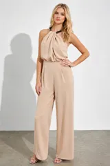 Mono largo color nude de silueta relajada, con escote halter y detalle de cadena negra en el cuello que aporta un toque sofisticado y moderno.
