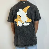 Remera de corte semi oversize con efecto lavado ácido en color negro. Presenta un estampado gráfico en la espalda que combina una silueta de personaje animado en blanco con una estrella amarilla de fondo.