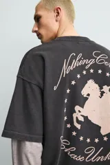 Sudadera de manga corta con corte relajado, confeccionada en algodón con interior de rizo. Presenta cuello redondo con detalle de costura en V, efecto lavado y estampado gráfico en el frente.