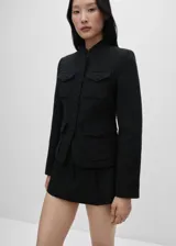 Chaqueta de estilo militar confeccionada en tejido tweed, con cuello redondo, cierre frontal de botones y cuatro bolsillos de parche en la parte delantera. Presenta un diseño entallado de corte recto y manga larga.