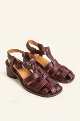 Sandalias de cuero color negro con diseño de tiras cruzadas tipo huarache, tira ajustable con hebilla metálica en el empeine y taco cilíndrico de madera.