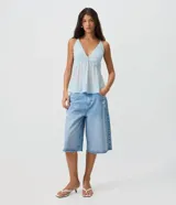 Bermuda jorts de jean en color celeste, con cintura media, calce amplio, bolsillos delanteros y traseros, y detalles de desgastes localizados.