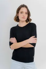 Buzo de tejido abierto color beige claro, de calce oversize con mangas 3/4 y cuello redondo. Presenta terminaciones acanaladas en puños y cintura.