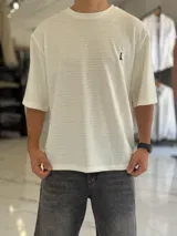 Remera oversize de tejido texturizado en color verde militar, con cuello redondo y mangas cortas. Presenta un pequeño bordado blanco en el pecho.