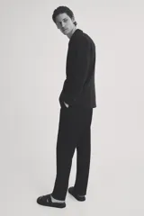 Blazer negro de doble botonadura con solapas de pico, bolsillo superior, bolsillos delanteros ribeteados con solapa, tres bolsillos interiores, botones decorativos en los puños y abertura doble atrás.