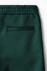 Short de corte relajado de color verde oscuro, con cintura elástica y cordón ajustable. Cuenta con ribetes de cinta blanca a lo largo de los laterales y bolsillos frontales.