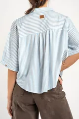 Blusa de manga corta con diseño a rayas verticales celestes y blancas, cuello camisero con escote en V y cierre frontal de botones.