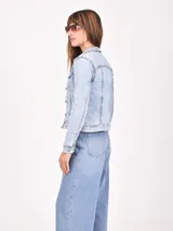 Campera de jean de mujer, color azul claro lavado, con corte clásico, cuello camisero, botones frontales y bolsillos con tapa en el pecho.