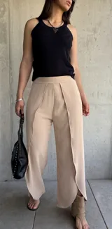 Pantalón color beige de corte palazzo con abertura lateral en la parte inferior de la pierna.