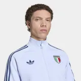 Campera deportiva Adidas Originals de la selección de Italia, color celeste con detalles en azul marino. Presenta cuello alto, cierre frontal, las icónicas tres tiras en las mangas, logo del Trifolio y escudo de la selección italiana en el pecho.
