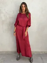Vestido largo color borgoña, de corte recto y mangas 3/4 abullonadas. Incluye cinturón de la misma tela.