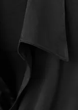 Camisa de tejido satinado color negro, de corte recto con diseño cruzado que se ajusta mediante un lazo lateral. Presenta cuello camisero, escote en V y mangas largas con puños anchos abotonados.