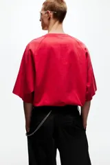 Remera de algodón oversized color rojo, con cuello redondo y mangas cortas raglán decoradas con una franja blanca lateral con logotipos negros de Lotto. Cuenta además con el logo de la marca estampado en el centro del pecho.