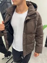 Campera puffer color marrón, con diseño acolchado, capucha forrada y cierre frontal con solapa de botones a presión. Cuenta con bolsillos laterales y puños internos.
