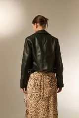 Campera de estilo biker confeccionada en eco-cuero negro, con solapas, cierre frontal, bolsillos con cremallera y detalles acolchados en los hombros.