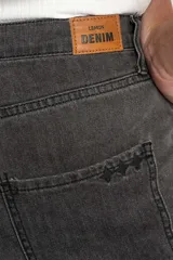 Pantalón de jeans gris oscuro, de corte flare y tiro medio, con ruedo desflecado.