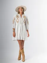 Vestido corto blanco de algodón italiano con bordado azul, mangas tres cuartos y botones frontales. Tiene forro interior en la falda.