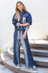 Pantalón de jean de corte recto y tiro alto, con diseño bicolor que combina paneles de denim azul oscuro y azul claro. Presenta cierre frontal con cremallera y ruedo desflecado.
