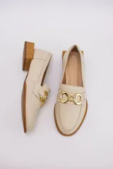 Mocasines de cuero en tono bronce metalizado, con detalle de aplique metálico dorado en el empeine y taco cuadrado bajo de madera.