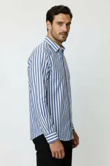 Camisa de algodón a rayas verticales azules y blancas, de manga larga, con cuello camisero y cierre frontal con botones.