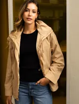 Campera color beige de poliéster, marca Michael Kors. Tiene cierre central oculto con botones a presión, bolsillos delanteros, capucha escondida en el cuello y avíos metálicos dorados con logo.