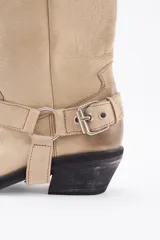 Bota de cuero marrón con caña alta y estribo desmontable.