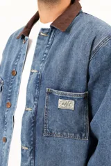 Campera de jean azul con cuello de corderito marrón, cierre con botones metálicos, cuatro bolsillos frontales y puños con botón.