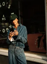 Camisa de jean estilo oversize con cuello camisero, cierre frontal con botones y mangas largas con puños. Presenta un diseño de denim clásico con costuras visibles.