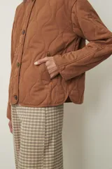 Campera acolchada color marrón claro, con cuello redondo, cierre frontal de botones y diseño de rombos.