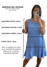 Vestido corto sin mangas, color gris topo, con escote redondo y detalle de volado en el ruedo. El tejido presenta una textura arrugada característica del lino.