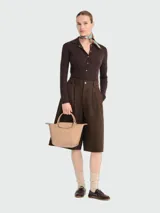 Cartera de mano modelo Le Pliage One de Longchamp, tamaño pequeño, en color beige. Presenta un diseño minimalista con solapa de cuero y cierre de botón a presión, asas cortas superiores y estructura trapezoidal.