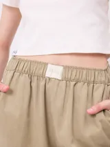 Pantalon de gabardina de corte recto y pata ancha, con cintura elástica y etiqueta decorativa en el frente.