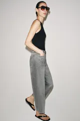 Jeans de tiro medio con corte relajado y largo al tobillo. Presenta diseño de cinco bolsillos, trabillas en la cintura y cierre frontal con cremallera y botón metálico.