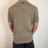Chomba de tejido de punto con textura, color beige, de manga corta y cuello polo con cierre frontal parcial.