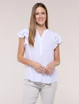 Blusa blanca de gasa con escote en V y media abotonadura frontal. Presenta mangas cortas con doble capa de volados superpuestos y silueta fluida.