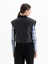 Chaleco de cuero vacuno negro con diseño matelaseado, cierre frontal, bolsillos laterales con cierre y terminaciones de puño tejido en cuello y cintura.
