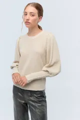 Sweater color crema de tejido de punto con lurex, mangas abullonadas y puños con botones metálicos.
