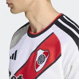 Camiseta de fútbol Adidas del River Plate, modelo local, color blanco con la característica banda diagonal roja, detalles en negro y cuello redondo.