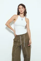 Pantalón tipo babucha de tiro bajo, color verde oliva, con silueta amplia y costuras visibles en contraste blanco. Posee cintura elástica con lazo blanco para ajuste.