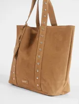 Cartera tipo shopper de gran tamaño confeccionada en material efecto gamuza color rojo. Presenta correas reforzadas decoradas con tachas metálicas plateadas y un dije colgante en forma de corazón con detalles de tachas. Cuenta con una placa metálica pequeña con logo en la parte inferior frontal.