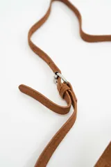 Cartera tipo bucket bag de gamuza negra, decorada con múltiples tachas metálicas plateadas de forma circular. Cuenta con cierre de cordón ajustable y asa superior.