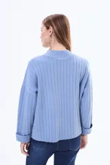 Buzo tejido de punto acanalado en color bordó, con cuello alto y mangas largas anchas con puños ajustados.