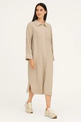 Túnica de lino con cuello camisero, cierre frontal con botones, manga larga y bolsillo en el pecho. Presenta un corte holgado y aberturas laterales en el ruedo.